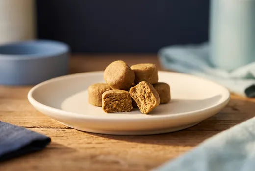 Soft cold-pressed joint chews for dogs on a ceramic plate, one broken open